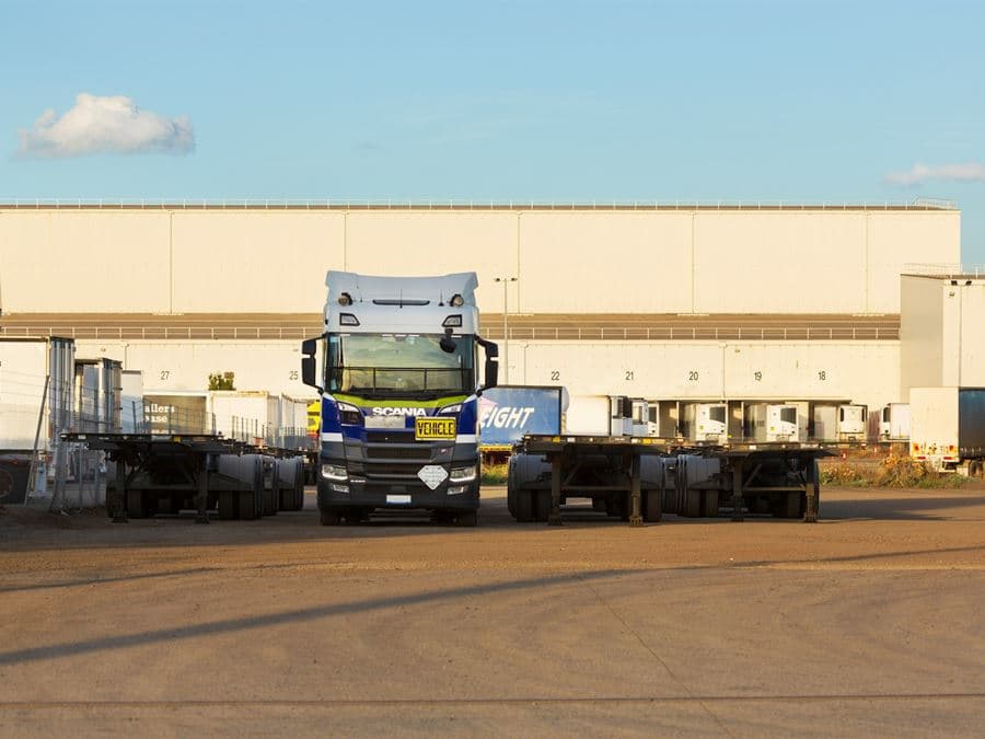 A heavy haul tractor and flatbed trailers staged at a freight terminal