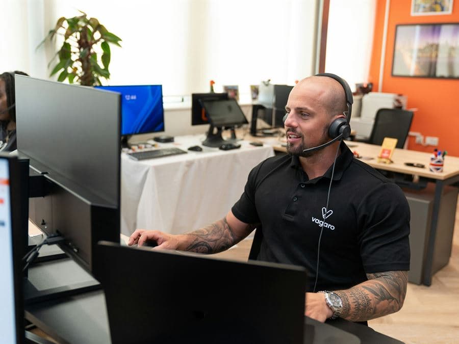 A dispatcher wearing a headset working at a desk with multiple monitors